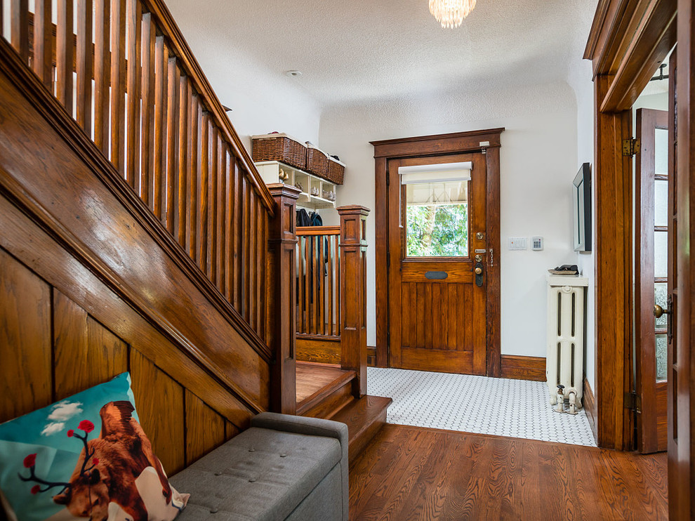 トロントにあるお手頃価格の中くらいなエクレクティックスタイルのおしゃれな玄関ロビー (白い壁、磁器タイルの床、木目調のドア、白い床) の写真