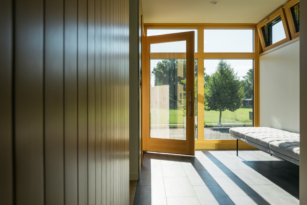 Ejemplo de puerta principal minimalista pequeña con paredes blancas, suelo de baldosas de cerámica, puerta simple, puerta de madera clara y suelo gris