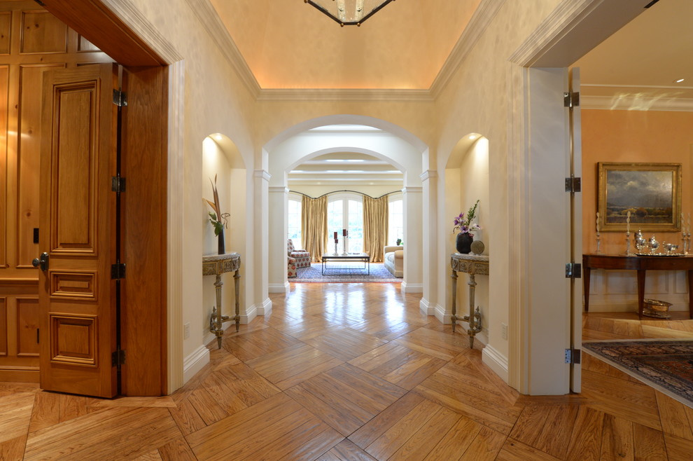 Ispirazione per un grande ingresso classico con pareti beige, pavimento in legno massello medio e pavimento marrone