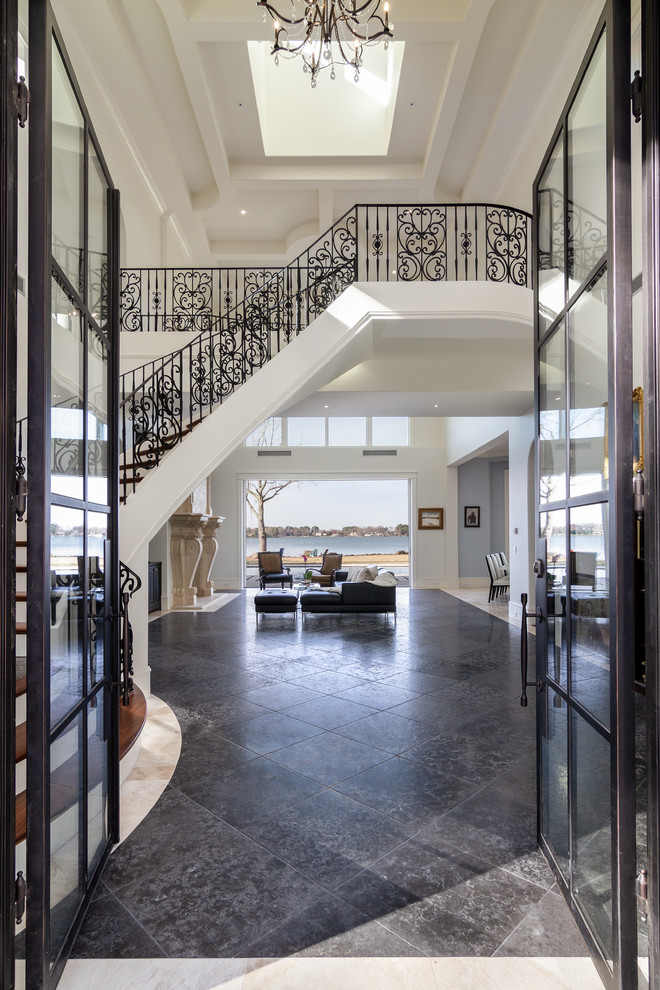 Photo of a large mediterranean foyer in Charlotte with white walls, a double front door, a glass front door, black floors and travertine flooring.