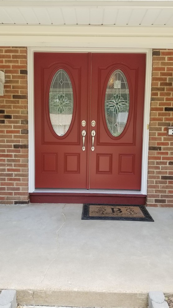 Cette image montre une porte d'entrée traditionnelle avec une porte double et une porte rouge.