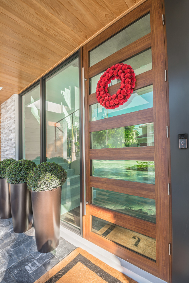 Large trendy slate floor entryway photo in Miami with gray walls and a glass front door