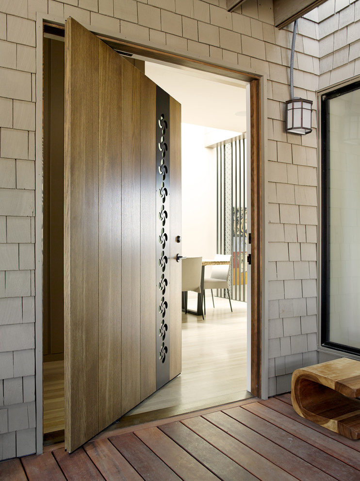 Ejemplo de entrada vintage con puerta pivotante y puerta de madera en tonos medios