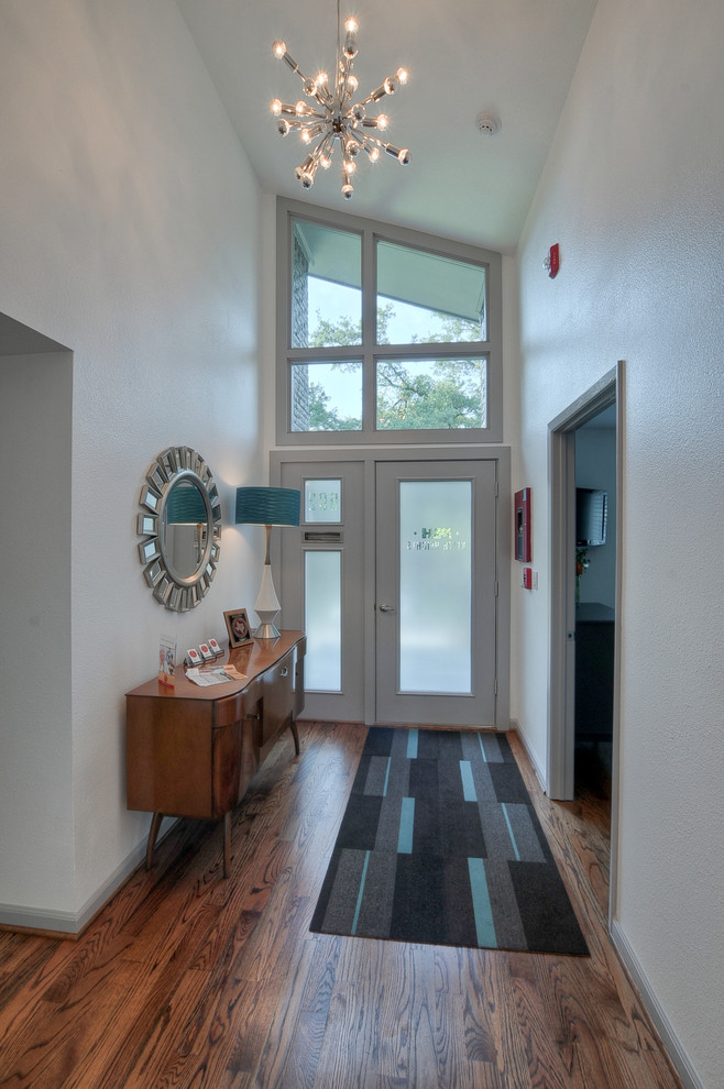 Aménagement d'une petite porte d'entrée rétro avec un mur blanc, un sol en bois brun, une porte simple et une porte en verre.