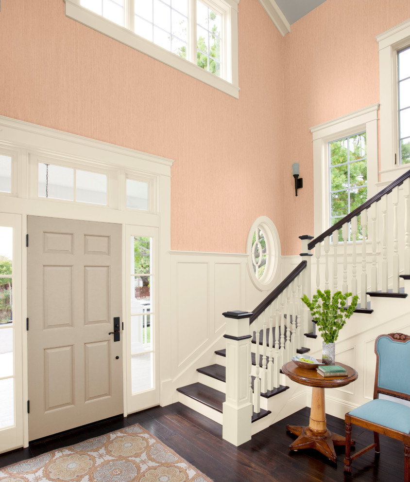 Пример оригинального дизайна: большое фойе в стиле неоклассика (современная классика) с оранжевыми стенами, темным паркетным полом, одностворчатой входной дверью и серой входной дверью