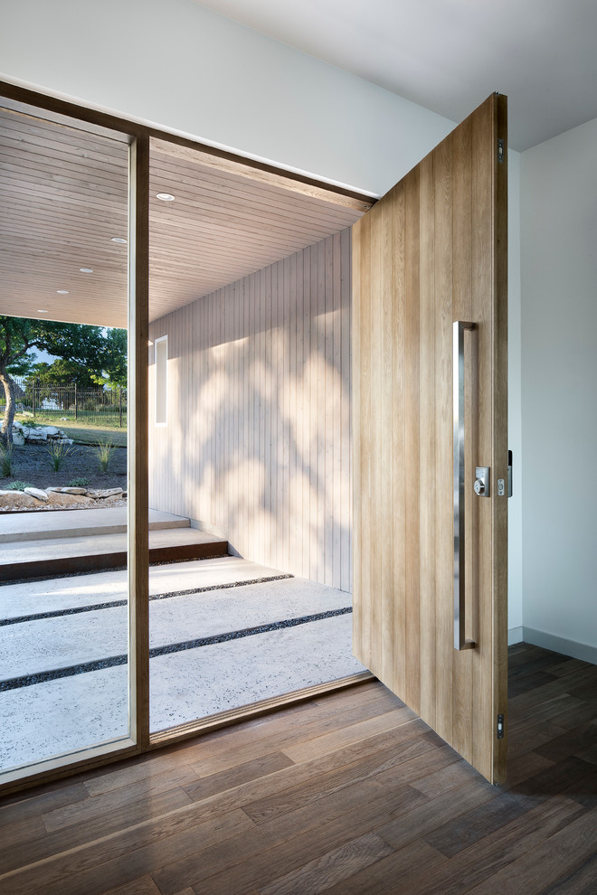 Immagine di una porta d'ingresso design di medie dimensioni con pareti bianche, pavimento in legno massello medio, una porta singola, una porta in legno bruno e pavimento marrone
