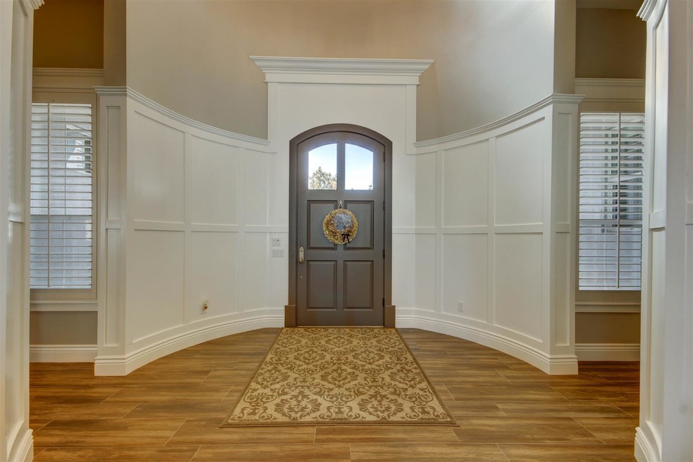 Inspiration pour un grand hall d'entrée traditionnel avec un mur gris, un sol en bois brun, une porte simple et une porte marron.