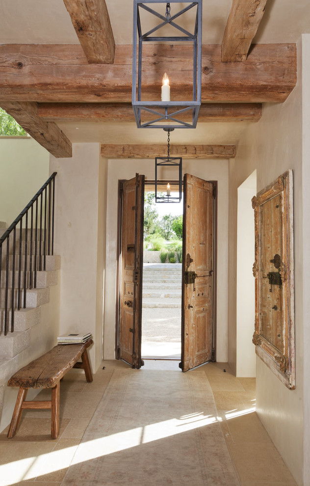 Idee per un ingresso mediterraneo con pareti beige, una porta a due ante, una porta in legno bruno e pavimento beige