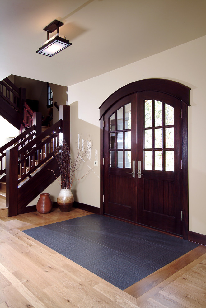 Aménagement d'un grand hall d'entrée classique avec un mur beige, parquet clair, une porte double et une porte en bois foncé.