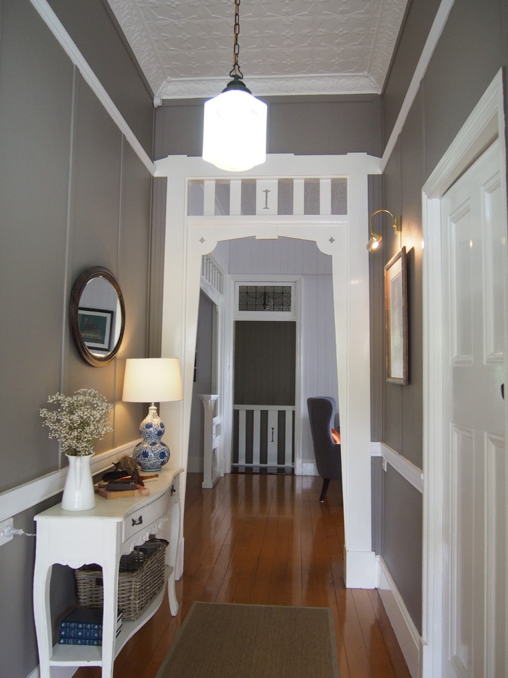 Idées déco pour un grand hall d'entrée classique avec un mur gris, parquet clair et une porte en bois brun.