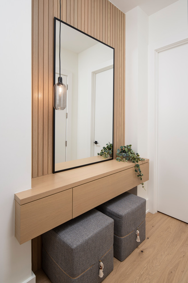 Ejemplo de distribuidor nórdico de tamaño medio con paredes blancas, suelo de madera en tonos medios, puerta simple y puerta blanca