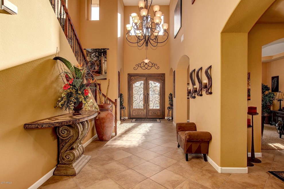 Großer Mediterraner Eingang mit Korridor, oranger Wandfarbe, Travertin, Doppeltür, hellbrauner Holzhaustür und beigem Boden in Phoenix