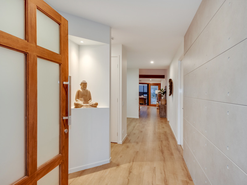 Cette image montre une grande porte d'entrée design avec sol en stratifié, une porte pivot et une porte en bois brun.