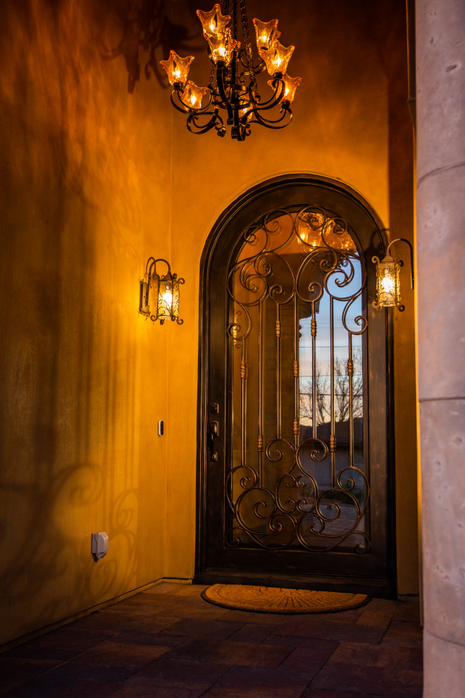 フェニックスにある高級な広いサンタフェスタイルのおしゃれな玄関ホール (ベージュの壁、磁器タイルの床、金属製ドア、ベージュの床) の写真