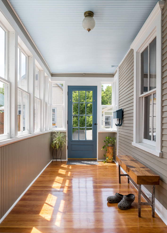 Cette photo montre une petite entrée chic avec un couloir, un mur beige, un sol en bois brun et une porte bleue.
