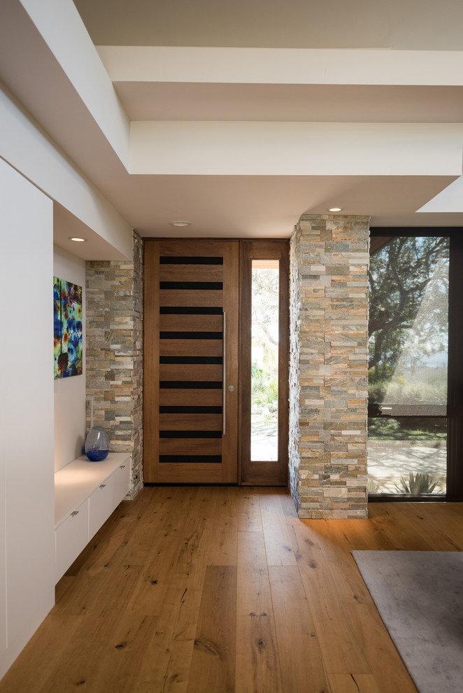 Inspiration pour un hall d'entrée design de taille moyenne avec un mur blanc, un sol en bois brun, une porte pivot, une porte en bois brun et un sol marron.