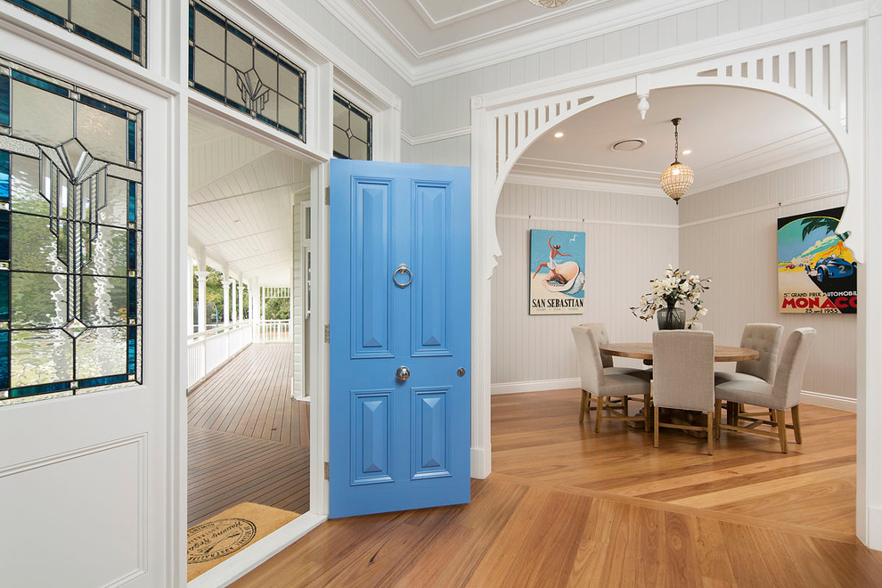 Inspiration pour une entrée marine avec un sol en bois brun, une porte simple, une porte bleue et un mur beige.