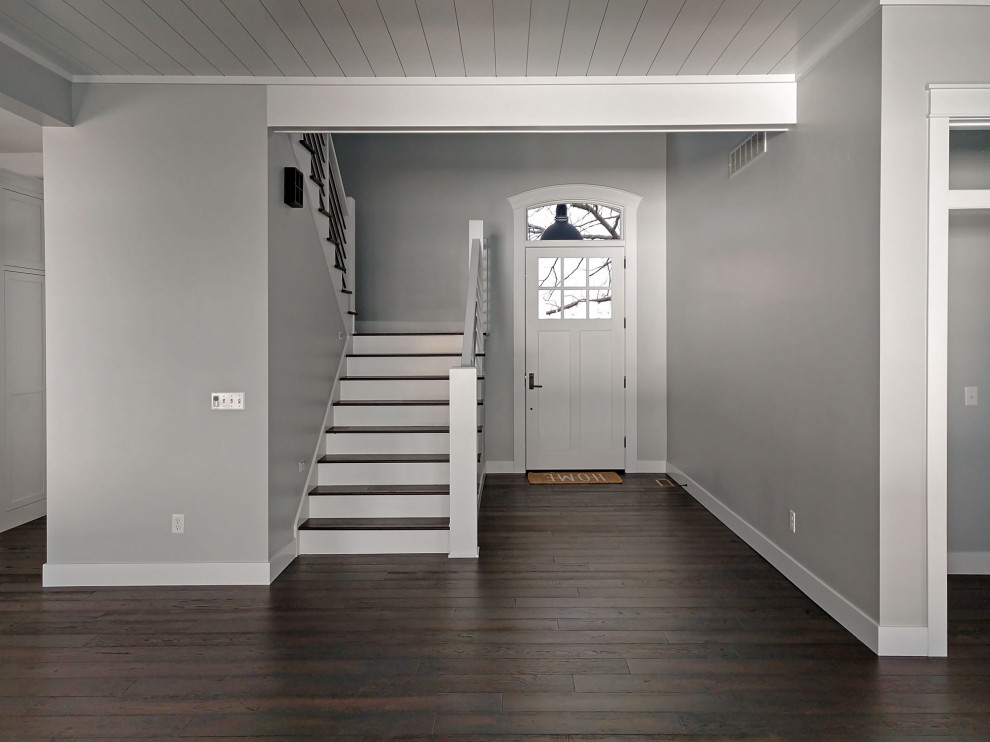 Idées déco pour une porte d'entrée craftsman avec un mur gris, parquet foncé, une porte simple, une porte blanche et un sol marron.