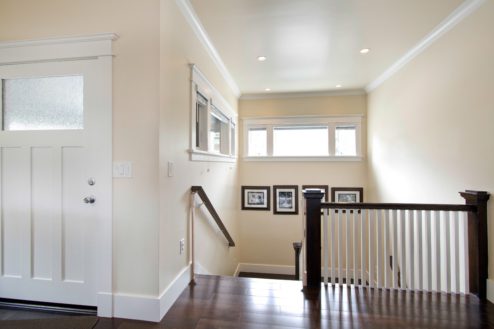 Aménagement d'une porte d'entrée craftsman de taille moyenne avec un mur beige, parquet foncé, une porte simple, une porte blanche et un sol marron.