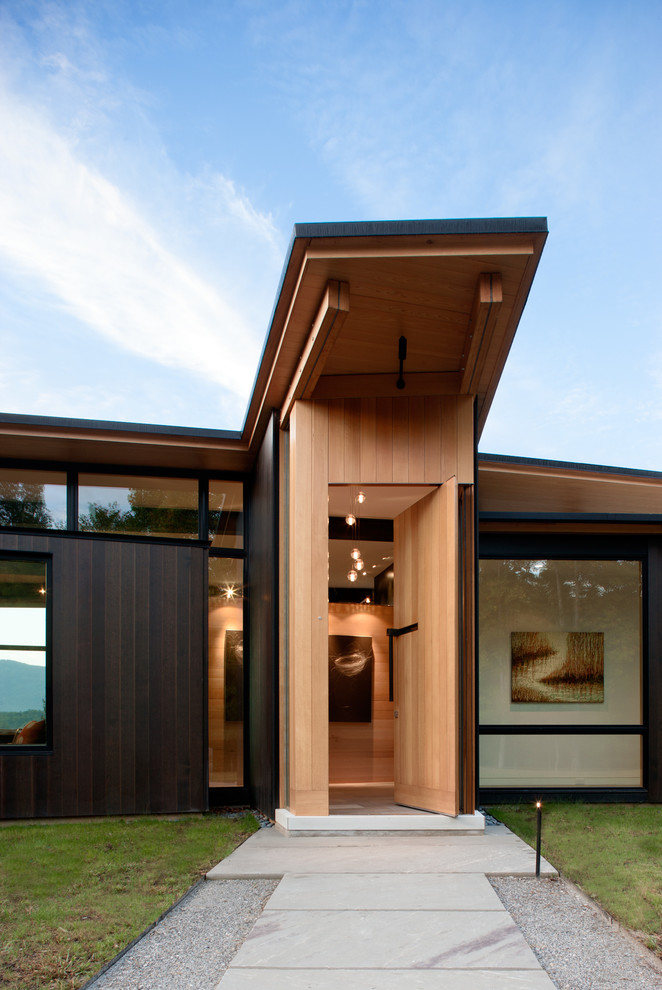Inspiration pour une porte d'entrée minimaliste avec une porte pivot, une porte en bois brun et un mur beige.