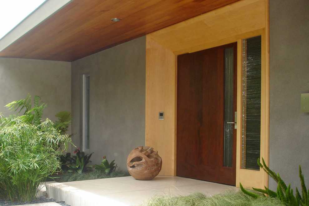 Aménagement d'une grande porte d'entrée moderne avec un mur gris, sol en béton ciré, une porte pivot et une porte en bois foncé.