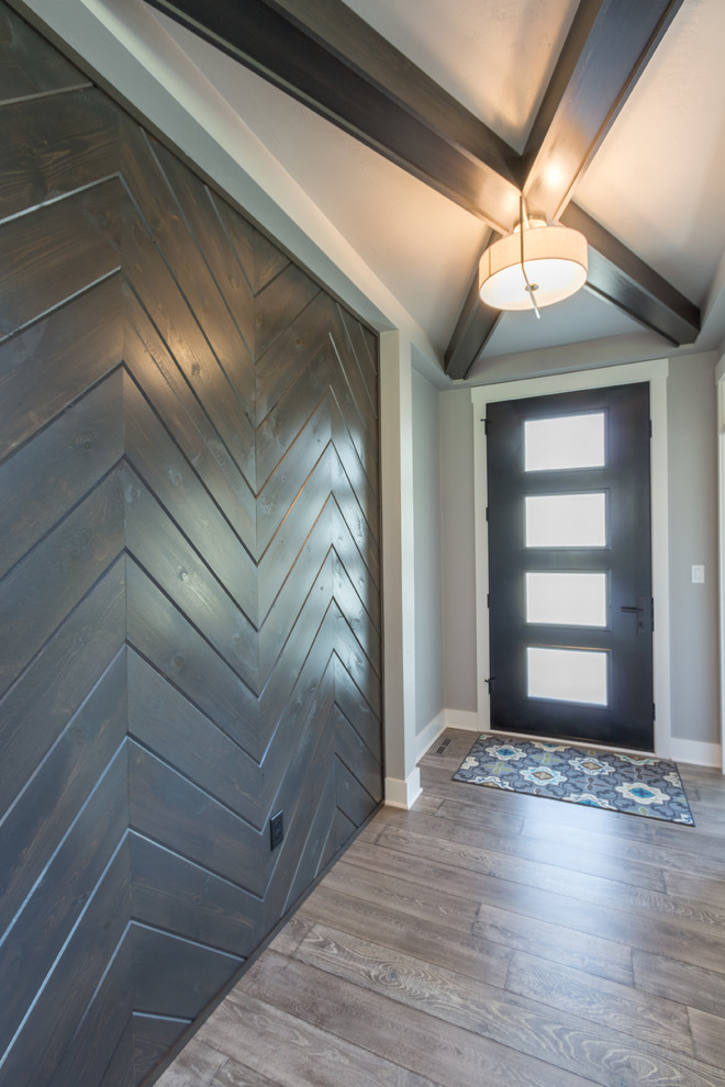 Ejemplo de distribuidor de estilo de casa de campo de tamaño medio con paredes grises, suelo de madera en tonos medios, puerta simple, puerta negra y suelo gris