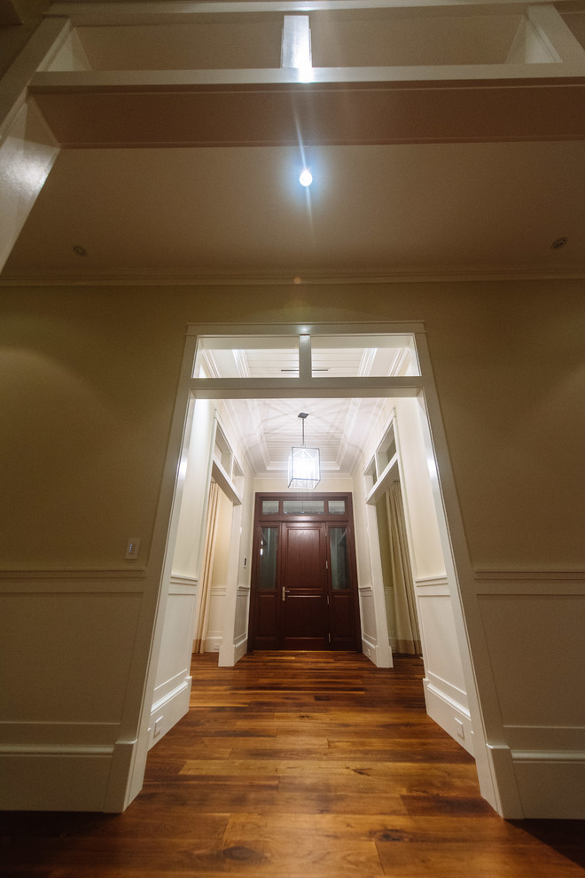 Diseño de hall clásico renovado de tamaño medio con paredes blancas, suelo de madera en tonos medios, puerta simple, puerta de madera oscura y suelo beige