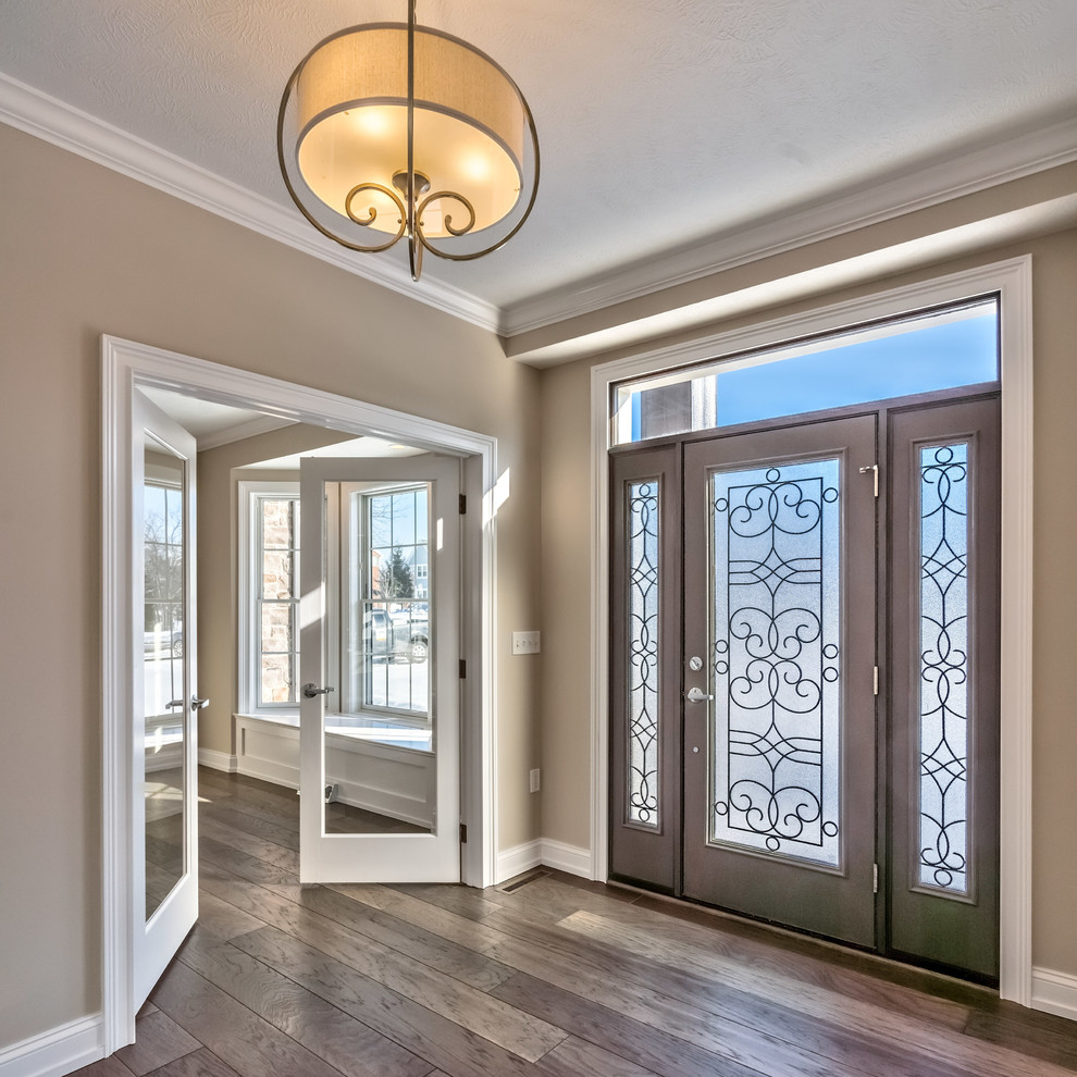 Großes Rustikales Foyer mit beiger Wandfarbe, braunem Holzboden, Einzeltür, hellbrauner Holzhaustür und grauem Boden in Sonstige