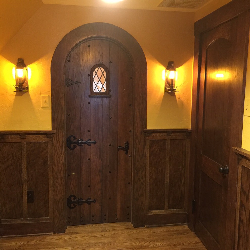 Imagen de hall de estilo americano de tamaño medio con paredes amarillas, suelo de madera clara, puerta simple y puerta de madera oscura