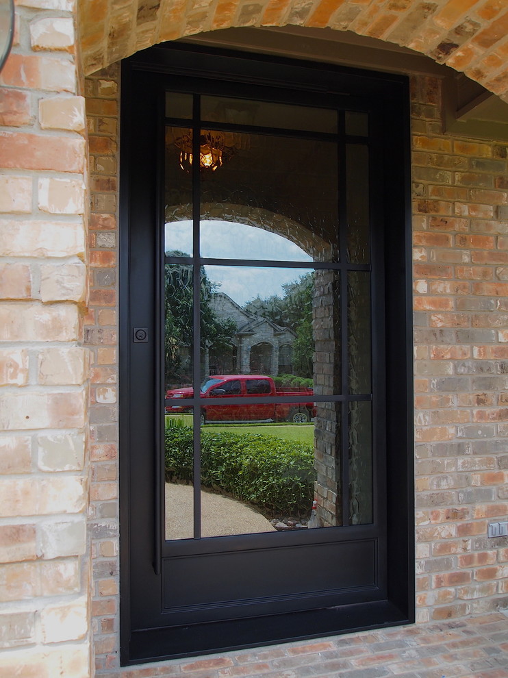 Пример оригинального дизайна: входная дверь среднего размера в современном стиле с коричневыми стенами, кирпичным полом, поворотной входной дверью и черной входной дверью