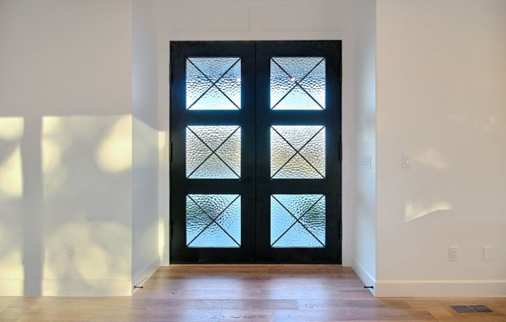 Foto de puerta principal abovedada campestre de tamaño medio con paredes blancas, suelo de madera clara, puerta doble, puerta negra y suelo beige