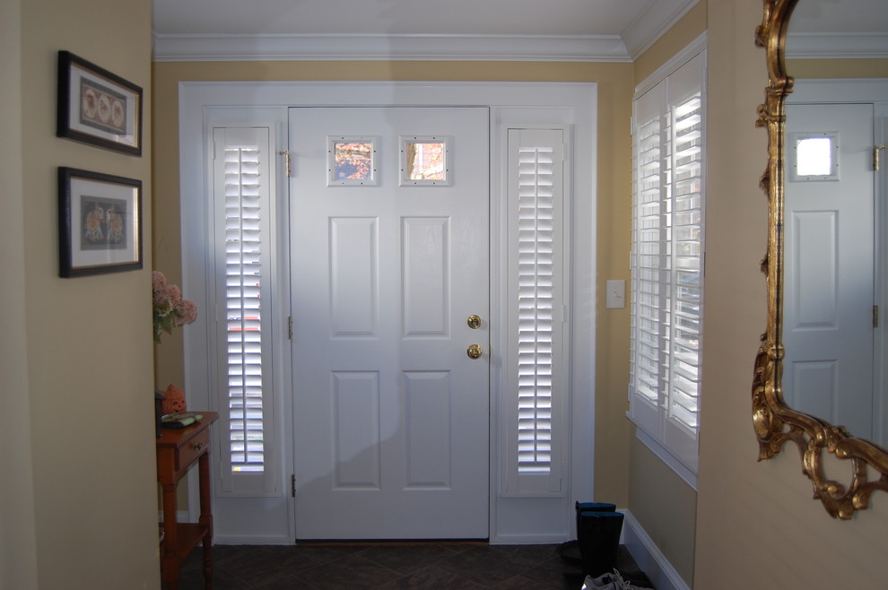 Imagen de distribuidor clásico de tamaño medio con puerta simple, paredes amarillas, suelo de baldosas de cerámica y puerta blanca