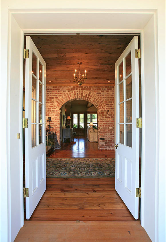 Ispirazione per un ingresso tradizionale di medie dimensioni con pareti rosse, pavimento in legno massello medio, una porta a due ante e una porta bianca