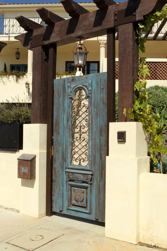На фото: большая прихожая: освещение в средиземноморском стиле с одностворчатой входной дверью, синей входной дверью, бежевыми стенами, бетонным полом и серым полом