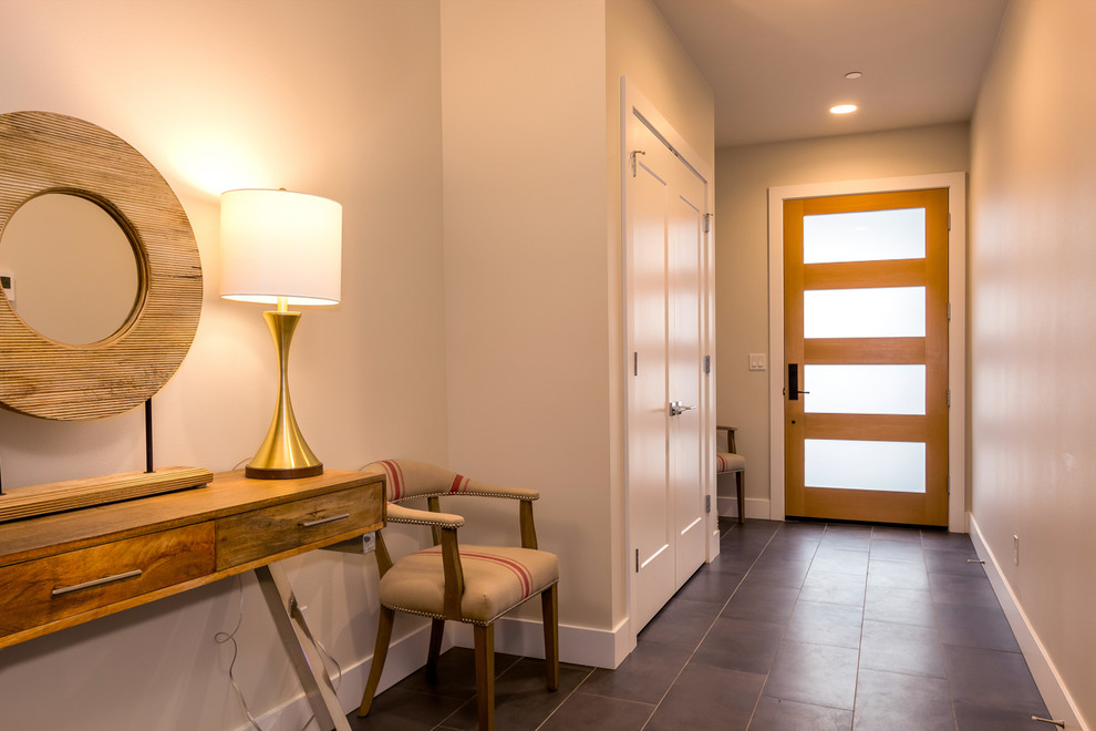Esempio di un corridoio minimalista di medie dimensioni con pareti bianche, pavimento in gres porcellanato, una porta singola, una porta in legno chiaro e pavimento marrone