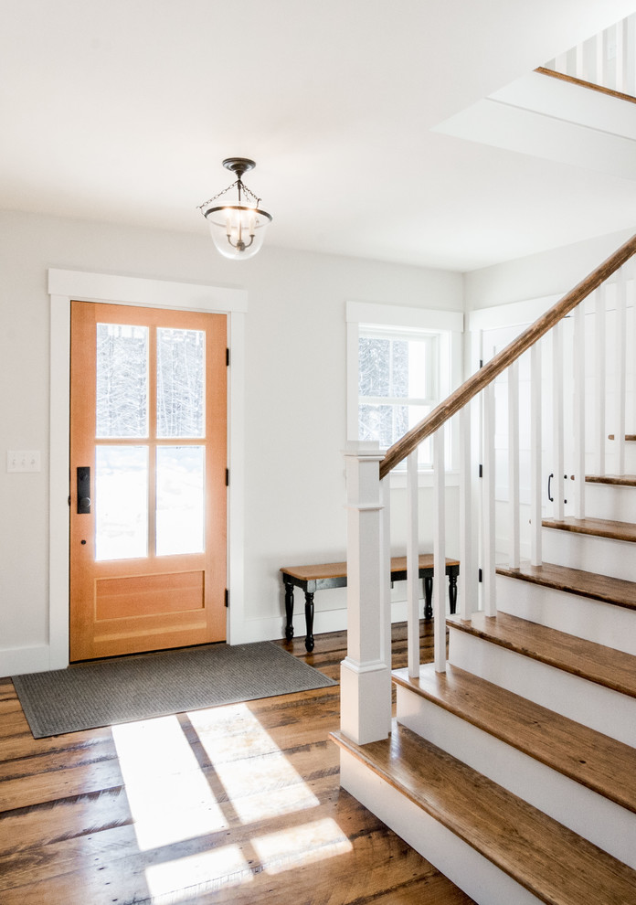 Immagine di un ingresso country di medie dimensioni con pareti bianche, pavimento in legno massello medio, una porta singola, una porta in legno chiaro e pavimento marrone