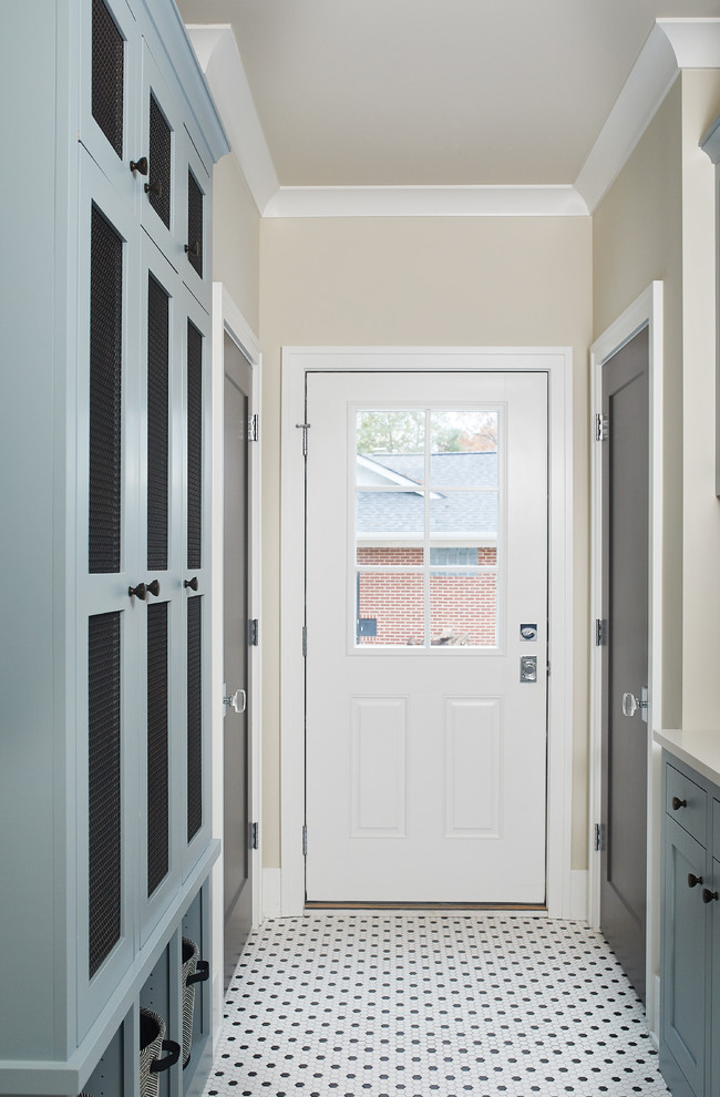 Cette image montre une grande entrée traditionnelle avec un sol en carrelage de porcelaine, une porte simple, un vestiaire, un mur beige, une porte blanche et un sol blanc.
