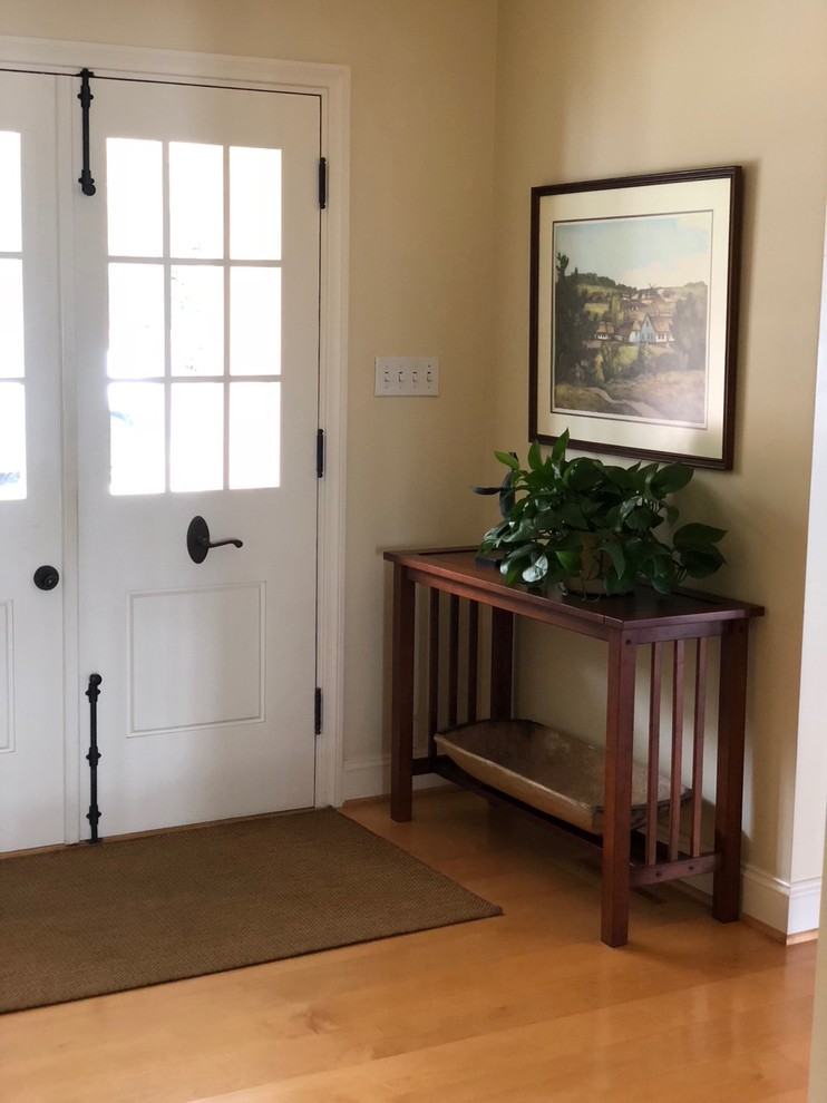 Réalisation d'une petite porte d'entrée tradition avec un mur beige, parquet clair, une porte double, une porte blanche et un sol marron.
