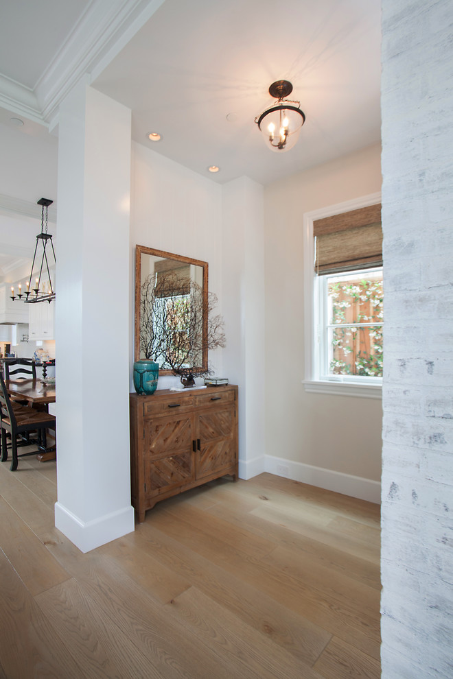 Photo of a classic foyer in Orange County with light hardwood flooring and feature lighting.