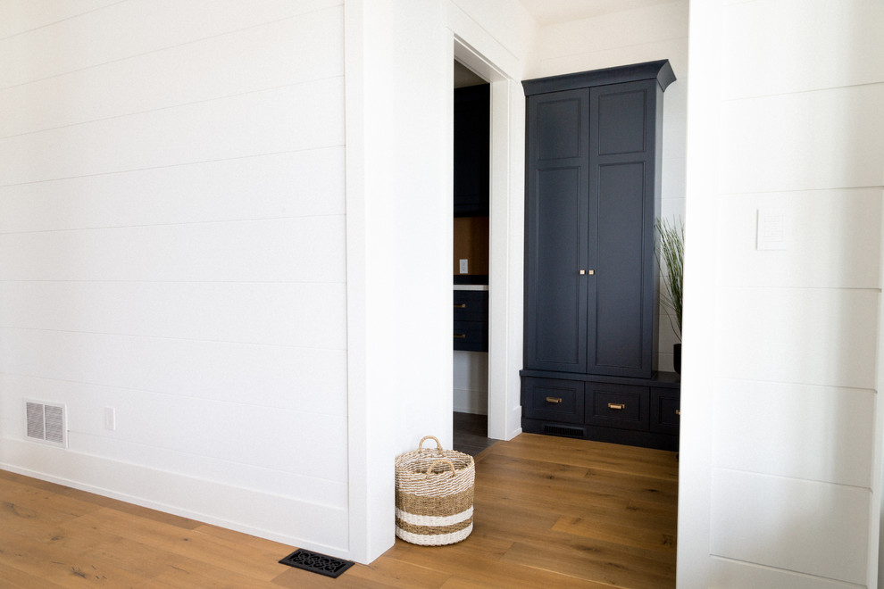 На фото: большой тамбур в стиле неоклассика (современная классика) с белыми стенами, светлым паркетным полом и коричневым полом с