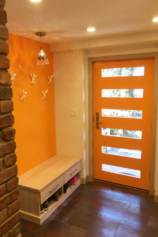 Cette image montre une entrée design de taille moyenne avec un vestiaire, une porte simple, une porte orange, un mur orange et un sol marron.