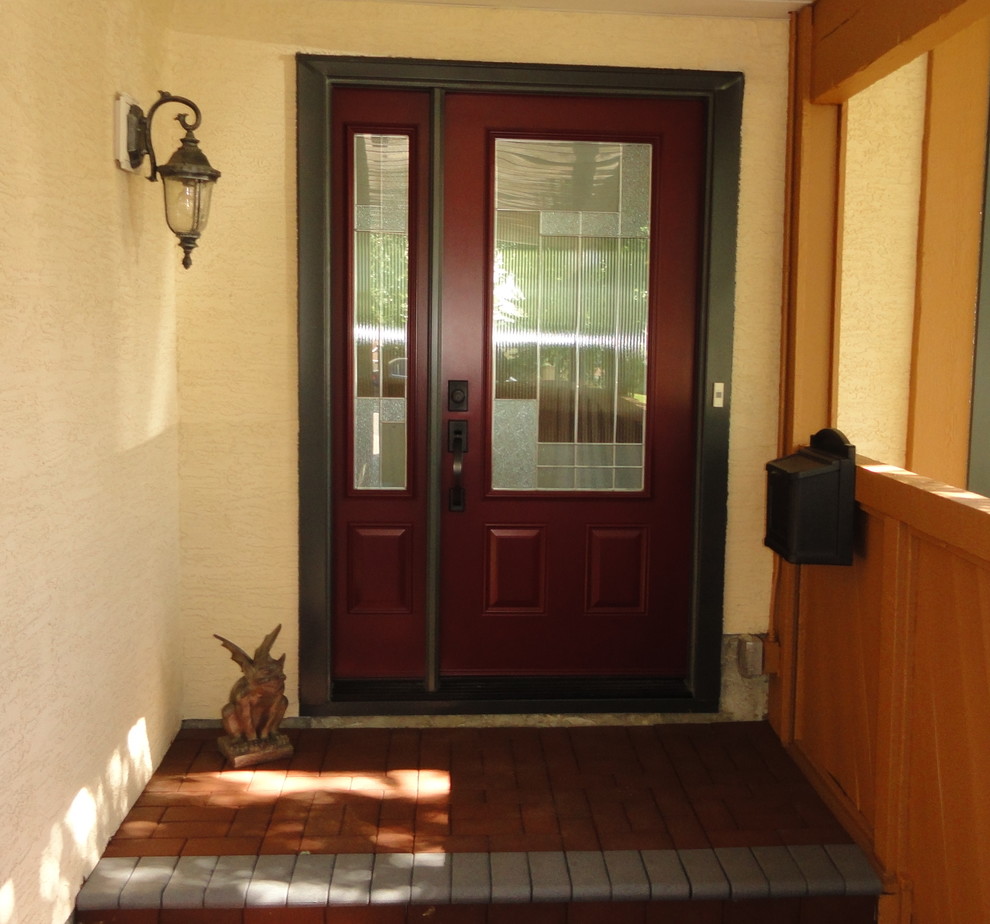 Klassische Haustür mit weißer Wandfarbe, Backsteinboden, Einzeltür, Haustür aus Metall und rotem Boden in Calgary