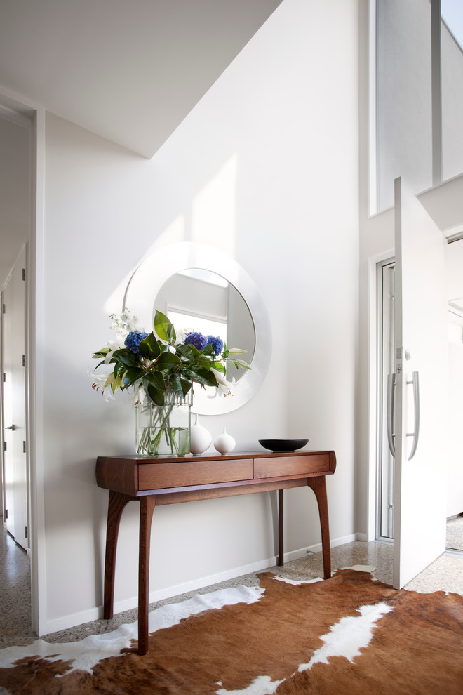 This is an example of a contemporary foyer in Auckland with white walls, a single front door and a white front door.
