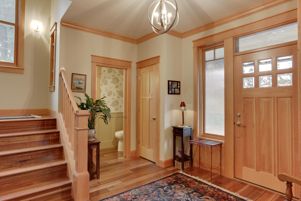 Idée de décoration pour un hall d'entrée craftsman avec un sol en bois brun, un mur beige, une porte simple et une porte en bois clair.