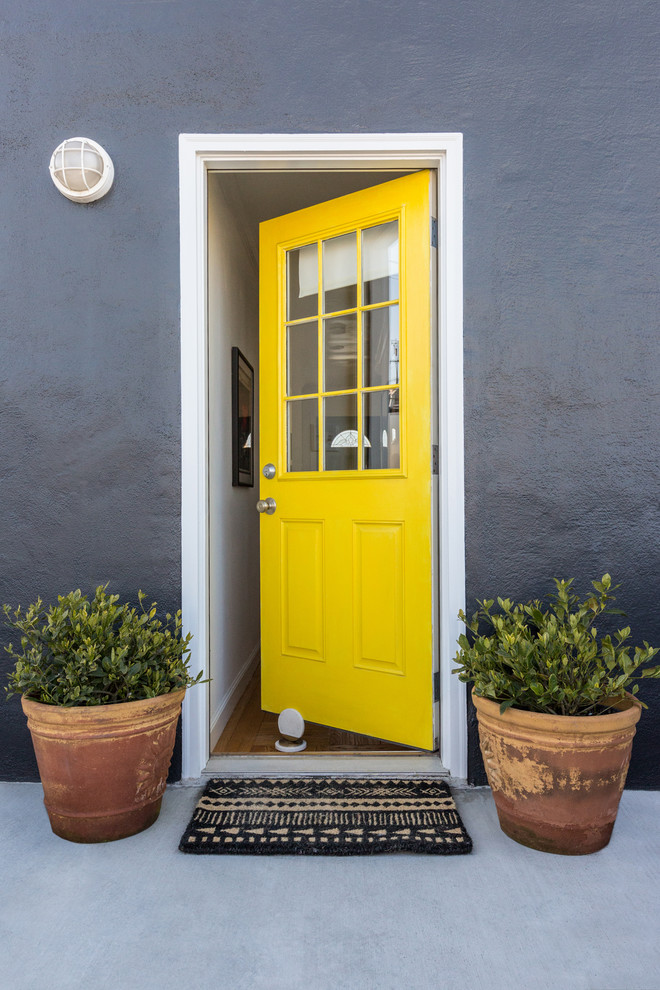 Ejemplo de puerta principal clásica renovada con paredes grises, suelo de cemento, puerta simple, puerta amarilla y suelo gris