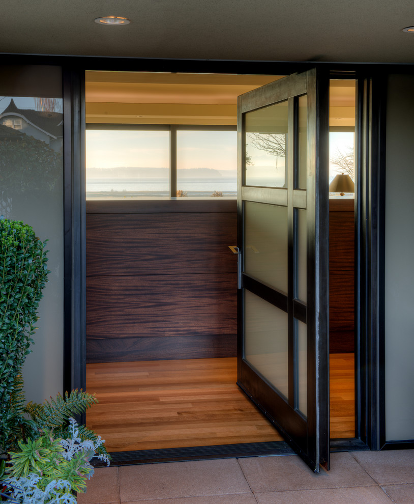 Ejemplo de puerta principal retro de tamaño medio con paredes beige, suelo de madera en tonos medios, puerta pivotante, puerta negra y suelo marrón