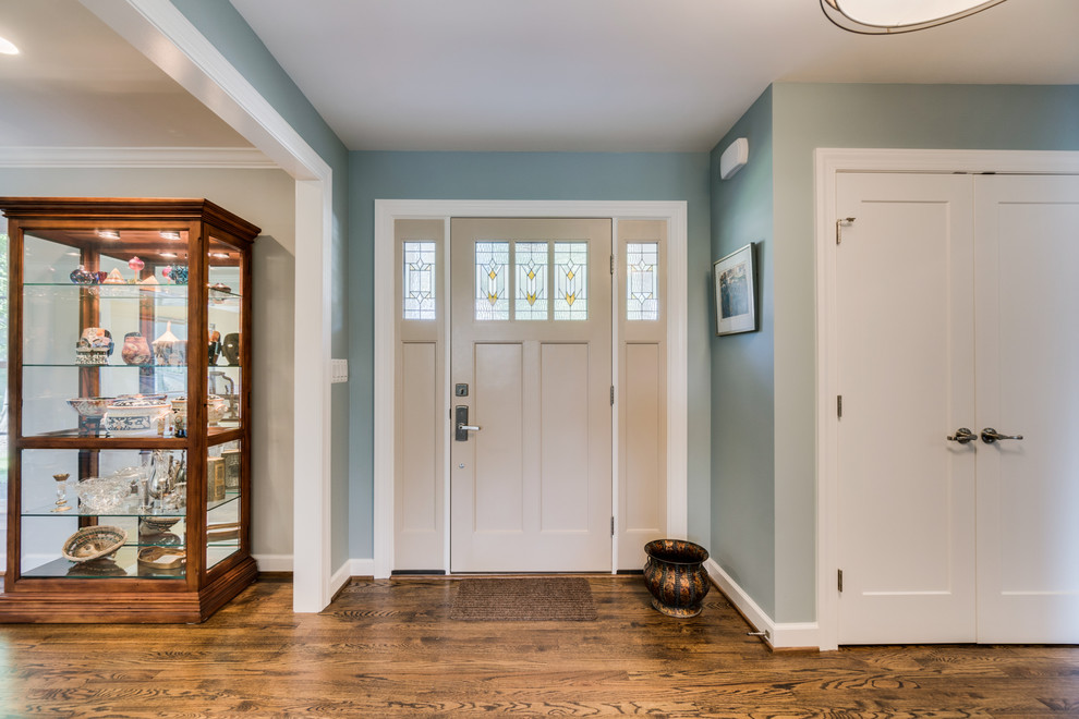 Foto di un ingresso classico di medie dimensioni con pareti blu, pavimento in legno massello medio, una porta singola, una porta bianca e pavimento marrone