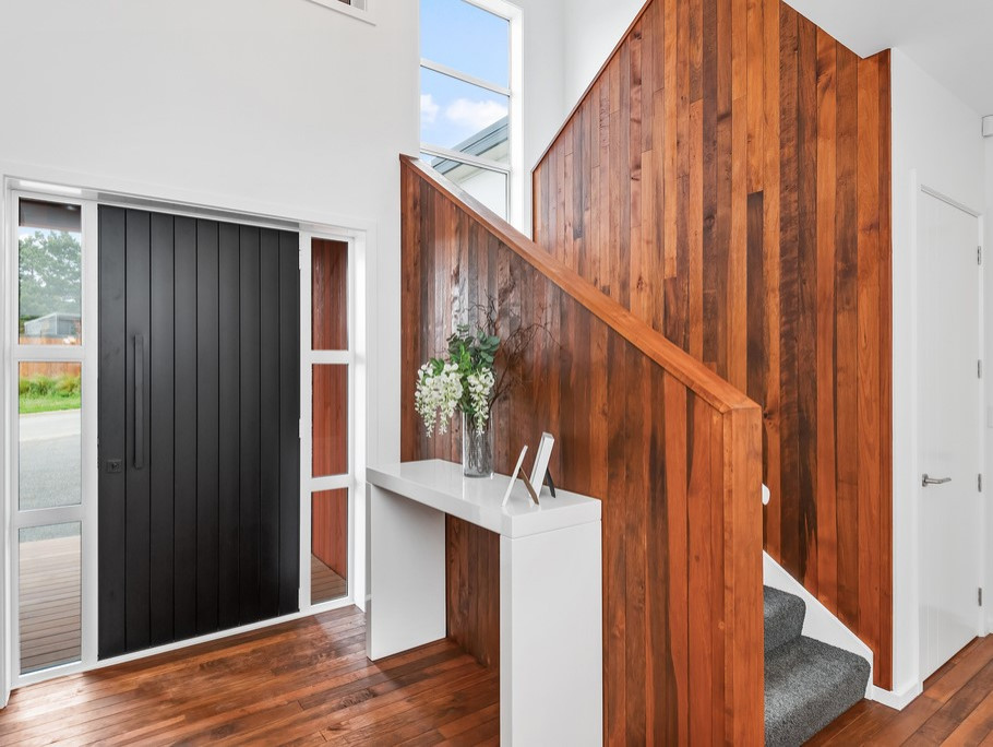 This is an example of a contemporary foyer in Christchurch with white walls, medium hardwood flooring, a single front door and a black front door.