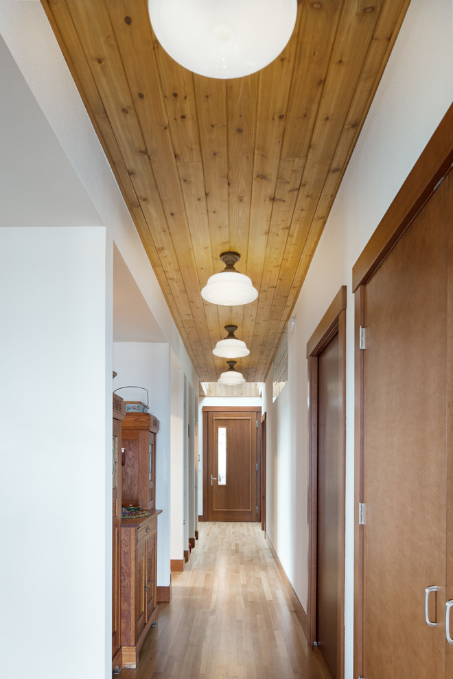 シアトルにある高級な中くらいなコンテンポラリースタイルのおしゃれな玄関ホール (白い壁、淡色無垢フローリング、木目調のドア、ベージュの床) の写真