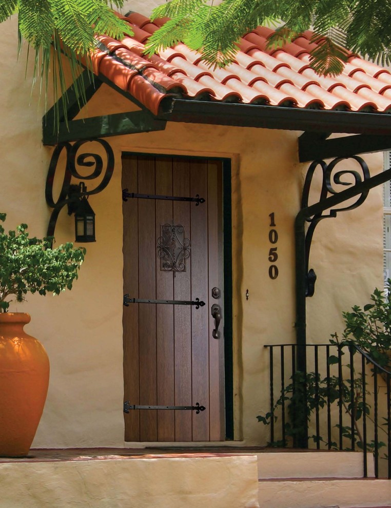 Пример оригинального дизайна: входная дверь среднего размера в средиземноморском стиле с желтыми стенами, одностворчатой входной дверью и входной дверью из темного дерева